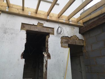 Partially demolished wall with exposed wooden beams and wiring.
