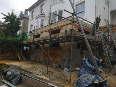 House extension under construction with scaffolding and building materials.