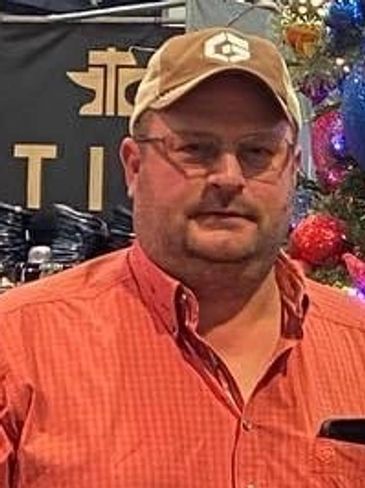 Man in glasses and orange shirt with a cap.