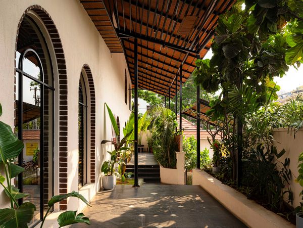 Sunlit porch with arched windows and lush plants.