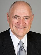 Portrait of a smiling bald man in a suit and tie.
