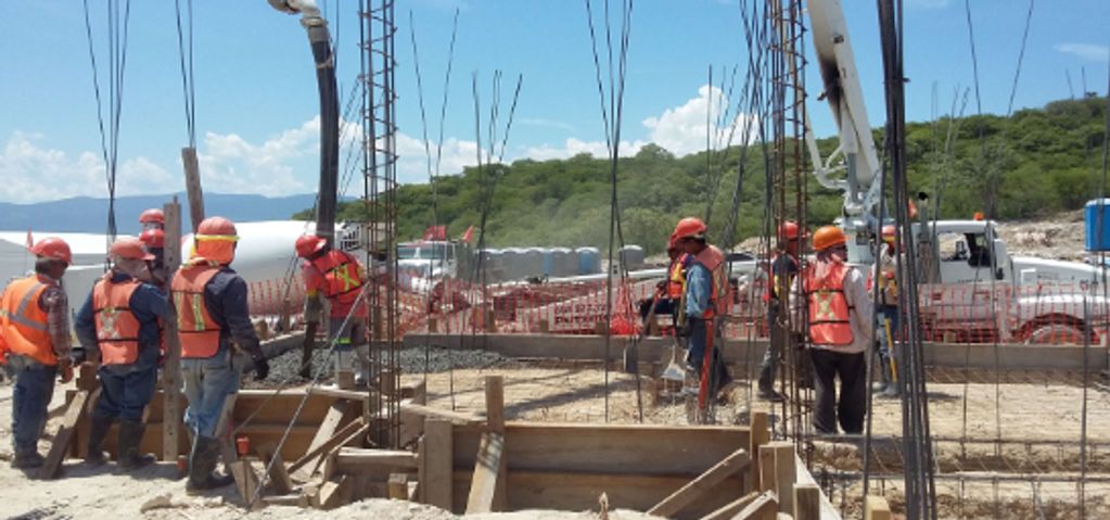 Trabajadores en construcción con equipo de seguridad en obra al aire libre.