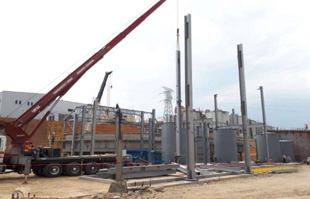 Construcción con grúas y estructura metálica en sitio industrial.