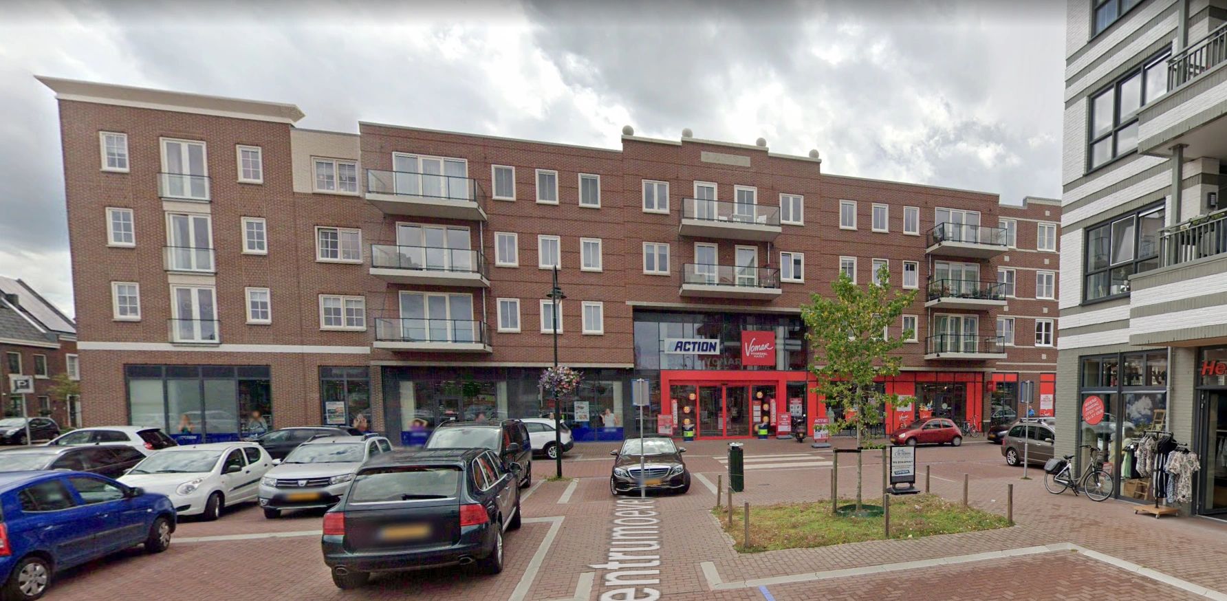 Gezicht op een winkelcentrum met auto's geparkeerd.