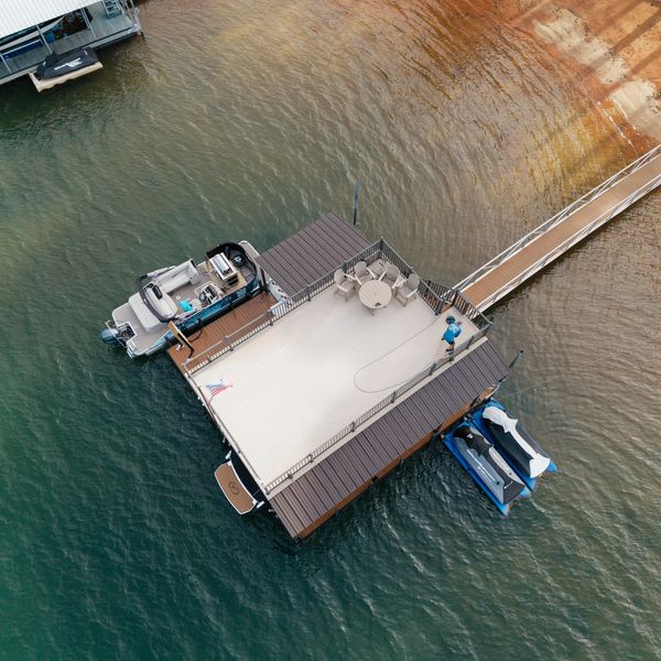 Aerial view of a lake dock with boats and a person.