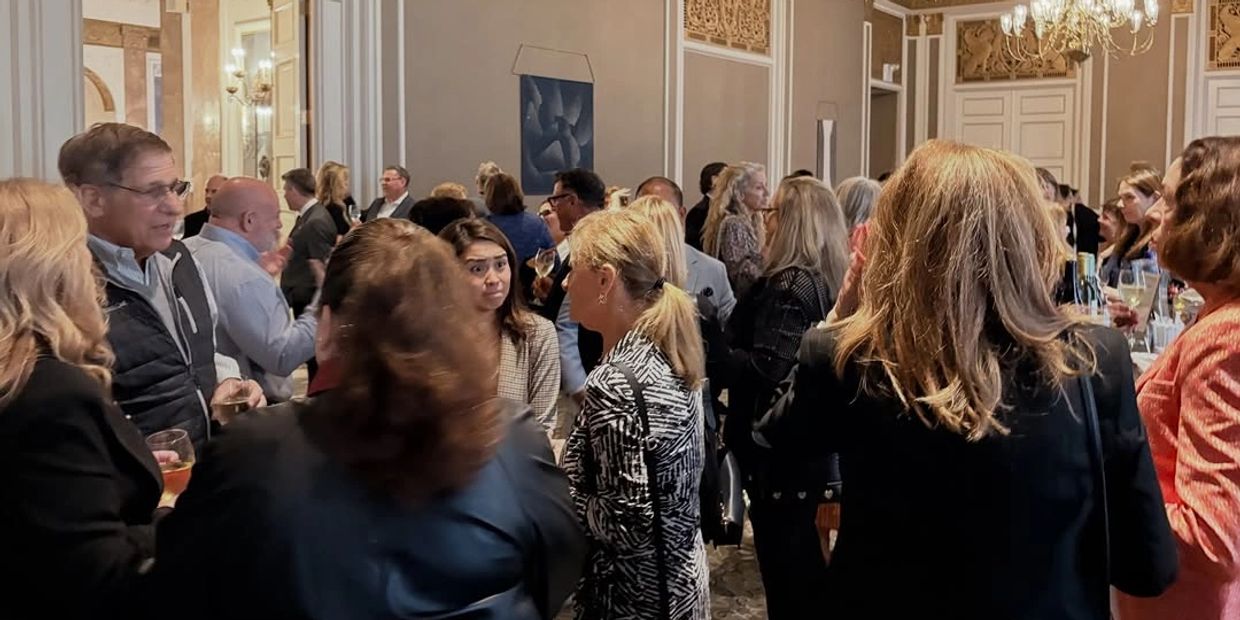Crowd mingling at an elegant indoor social event.