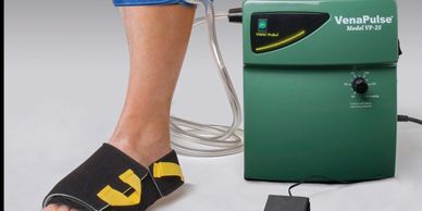 Person using VenaPulse device on foot for circulation therapy.