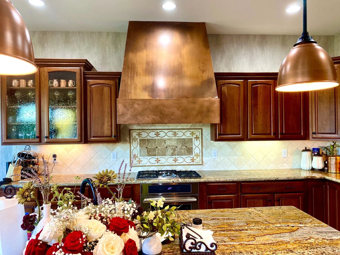 Custom copper range hood by Tin Works in a luxury kitchen with warm patina finish