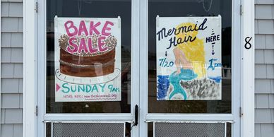 Image of clubhouse door with posters advertising bake sale and "mermaid hair"