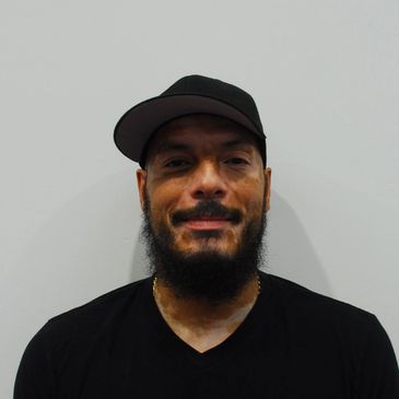 Man with a beard and cap smiling.