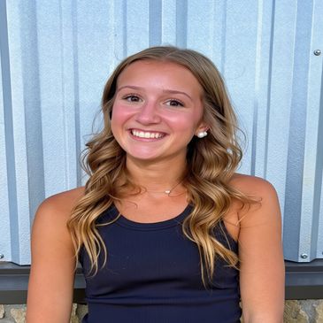 Smiling young woman with wavy hair in a black tank top.