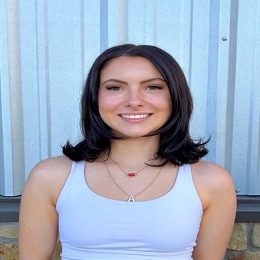 Young woman smiling against a metal wall.