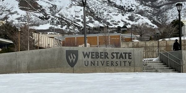 Weber State University sign with snowy mountains in the background.