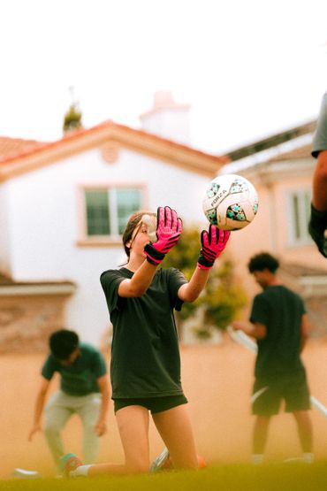 Girl goalkeeper catching a soccer ball during practice.