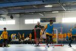 Indoor floorball game with players in action and spectators watching.