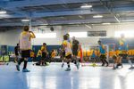 Indoor soccer match with players in yellow and black kits actively playing.
