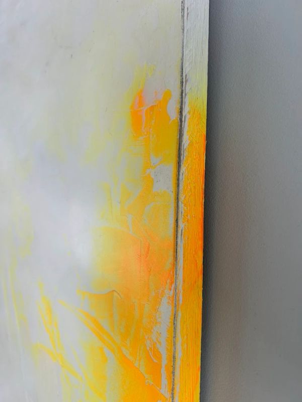 Detalle de pintura en amarillo y naranja sobre lienzo.
