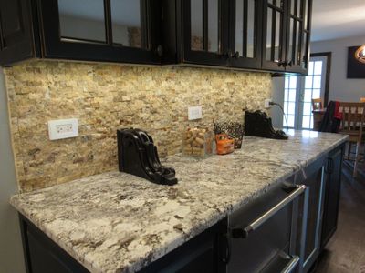 Stacked stone kitchen backsplash that accents the tan patterned granite countertop and expresso cabinets.