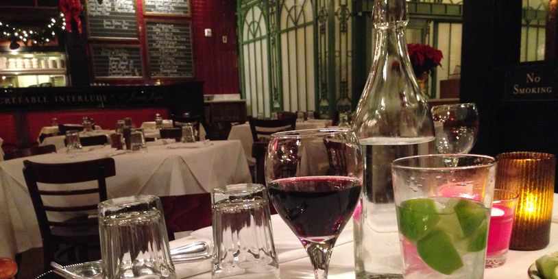 Cozy restaurant table with wine and lime drinks set for a romantic dinner.