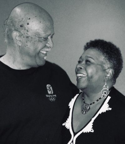 An elderly couple smiling warmly at each other in a candid moment.