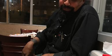 Man sitting at a table in a restaurant, smiling warmly.