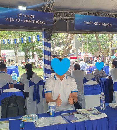 Person giving thumbs up at an electronics and telecommunication event booth.