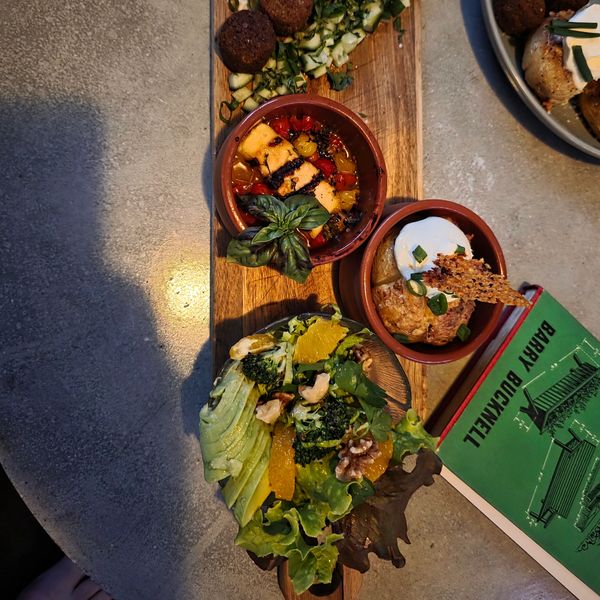 Appetizer platter with salad and dips on a wooden board.