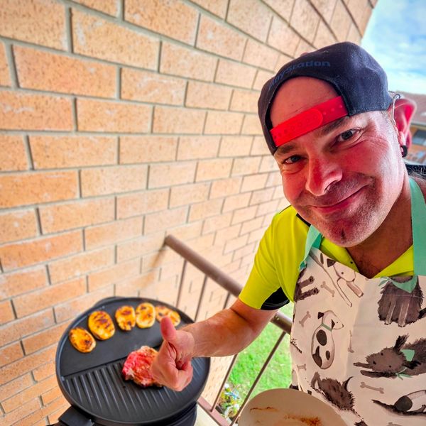 Man grilling food and showing thumbs up.