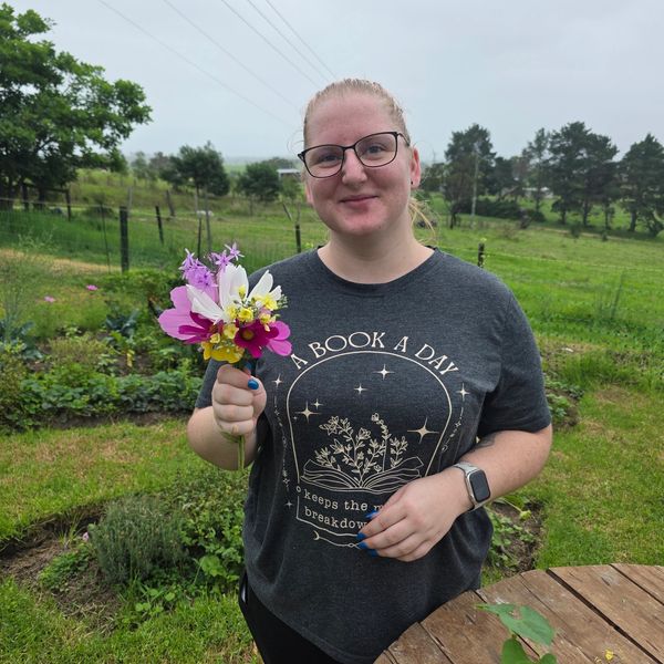 Woman holding a small bouquet of flowers outdoors.