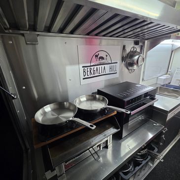 Stainless steel kitchen setup with two frying pans and ventilation hood.