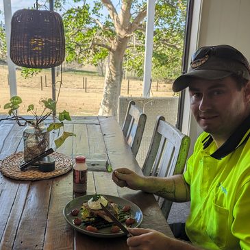 Man eating meal at wooden table near large window.