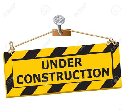 Yellow and black striped under construction sign hanging from a nail.