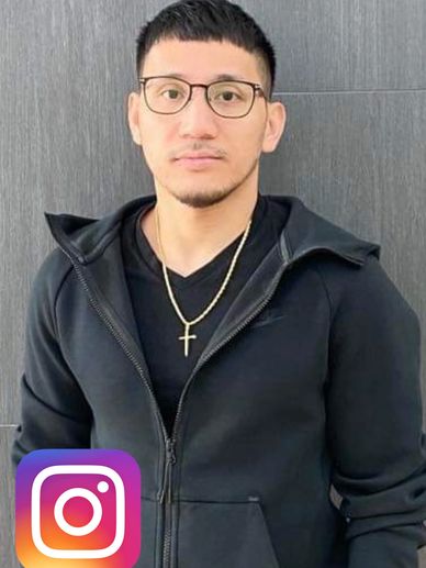Man with glasses and cross necklace wearing black hoodie.