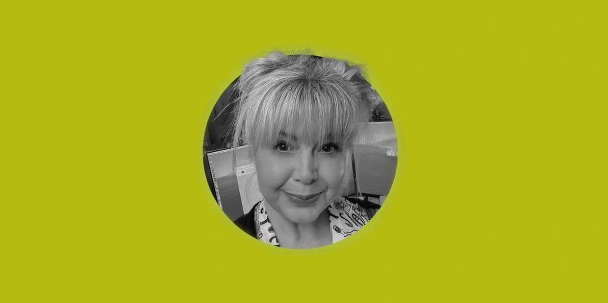 Black and white portrait of a smiling woman with bangs against a green background.