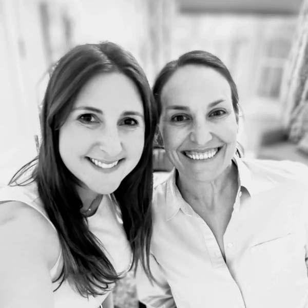 Two women smiling together in a bright indoor setting.