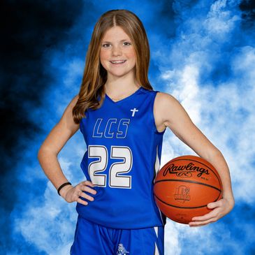 Young female basketball player in blue uniform holding a basketball.