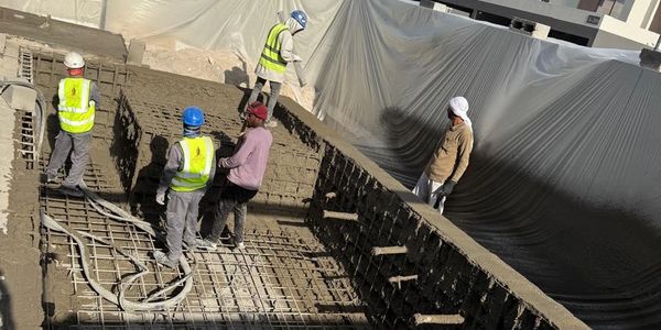Workers preparing a construction site with concrete and reinforcement.