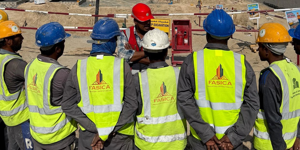 Construction workers in safety vests and helmets at a site.
