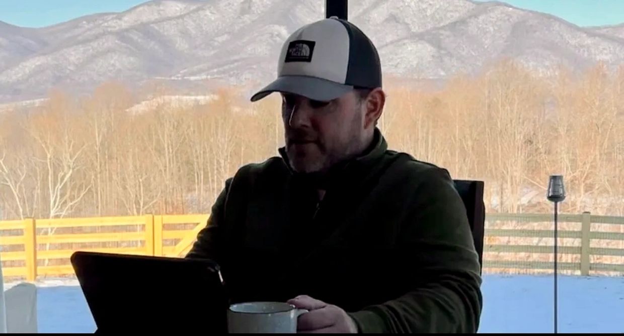 Man with a mug working on a tablet indoors.