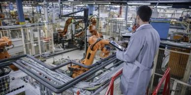 Engineer overseeing robotic arms in factory.