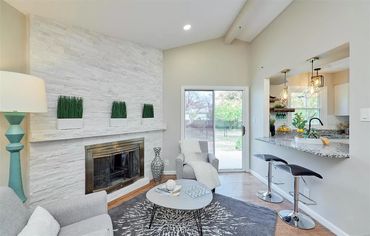 Modern living room with white stone fireplace and bar seating.