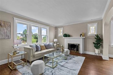 Bright living room with beige walls, white couch, and glass coffee table.