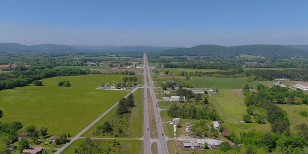 A straight highway cutting through green fields under a clear blue sky.