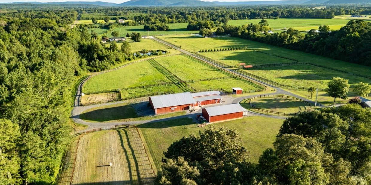 Aerial view of a rural farm with red barns and green fields.