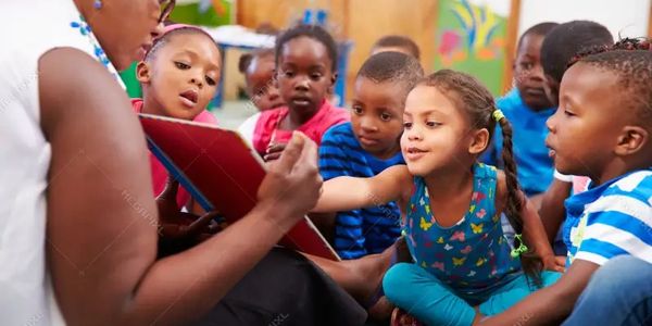Teacher reading to a group of attentive young children in a classroom.