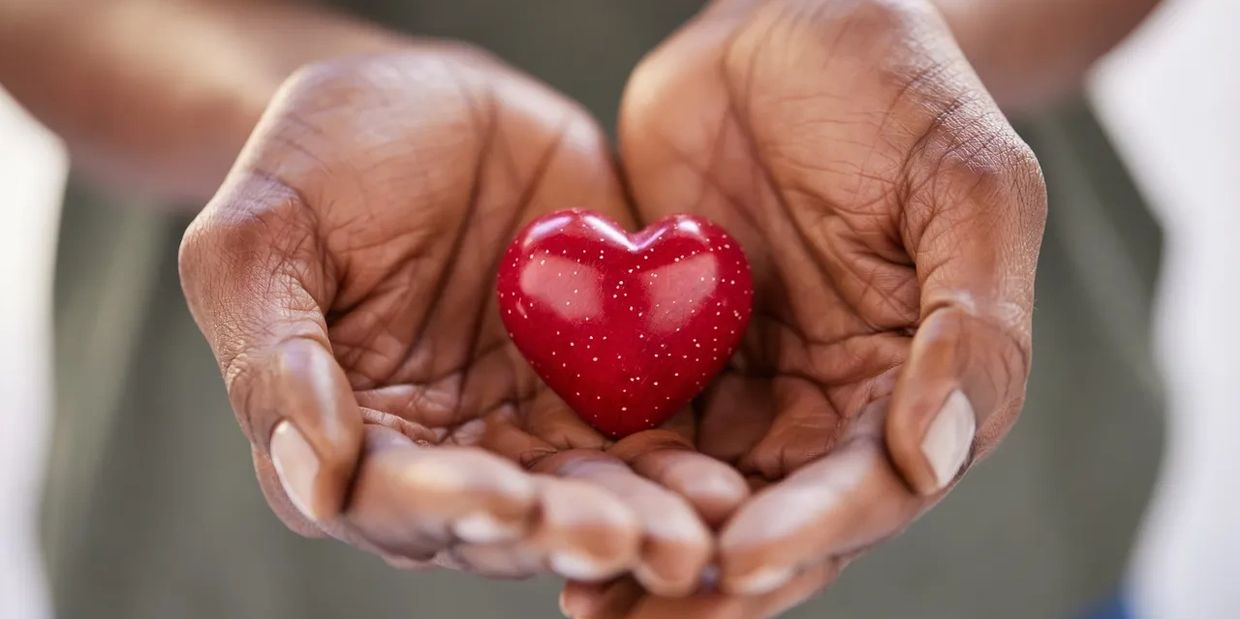 Hands holding a small red heart.