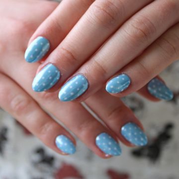 Hands with blue nails featuring white polka dots.