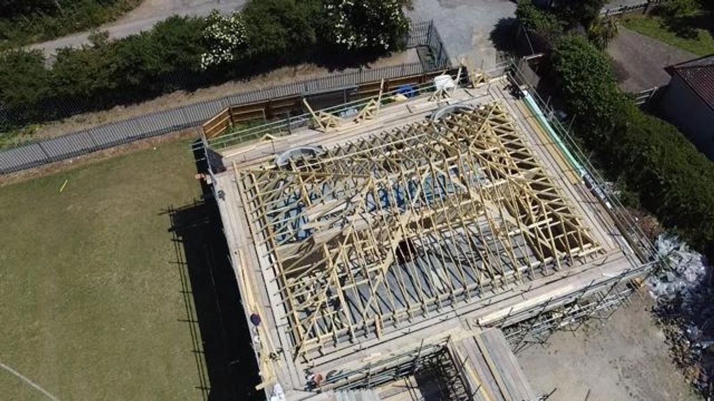 Drone photo of a large hipped trussed roof on a newly built school building.