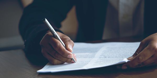 Person signing a document with a pen.