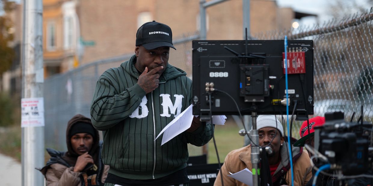 Man wearing a cap and hoodie on a film set.